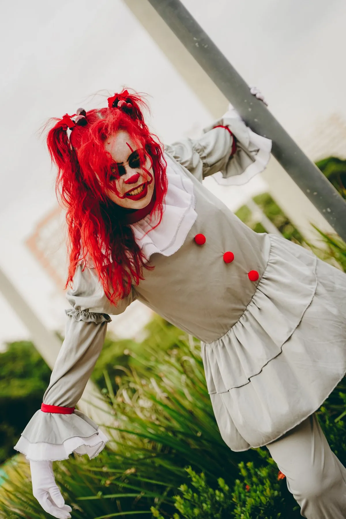 Cosplay de Pennywise de cabelo vermelho agarrada a um poste