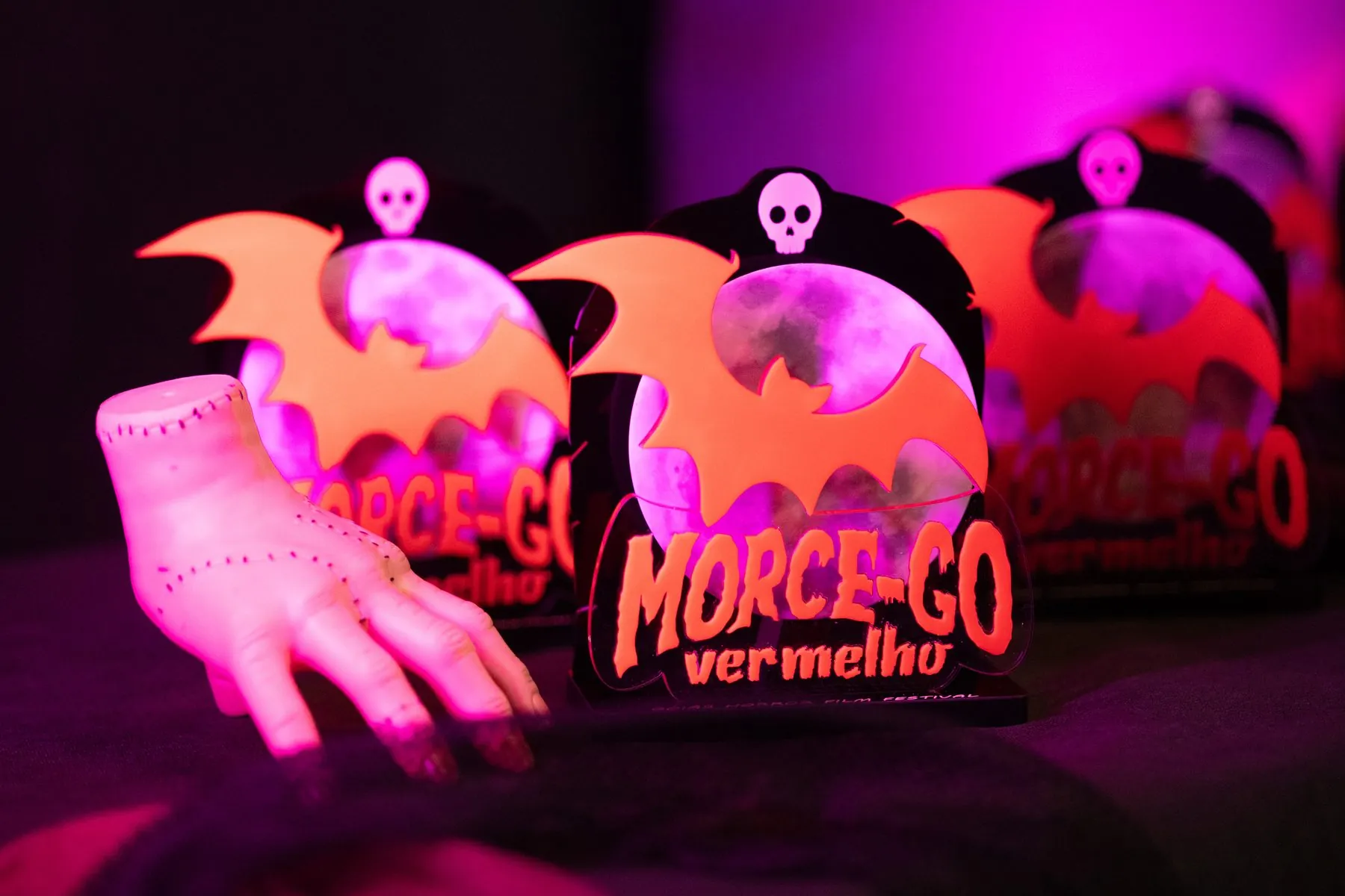 Troféus em forma de morcego iluminados em rosa e roxo